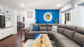 A modern living room with a sectional sofa, a wooden coffee table, and a blue accent wall.