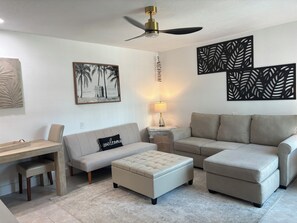 Una sala de estar con sofá, reposapiés y una mesa con banqueta.
