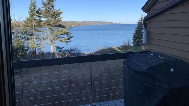 Ein Balkon mit Blick auf einen See, umgeben von Bäumen.