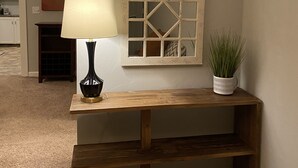 A wooden console table with a lamp and a potted plant, set against a wall with a decorative mirror. - 2 BD / 2 BA  (Charlotte)