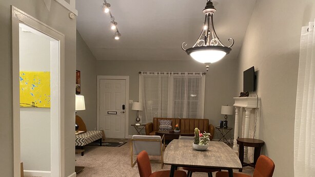 A dining area with a table, chairs, and a chandelier. There is a sofa and a television in the background. - 2 BD / 2 BA  (Charlotte)