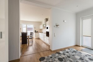 Une cuisine moderne avec des meubles blancs, un four encastré et un coin repas comprenant une table et des chaises.