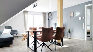 Ein modernes Loft mit Essbereich, einer Couch und einem großen Fenster.