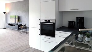 Een moderne keuken met witte kasten, een inbouwoven en een roestvrijstalen spoelbak.