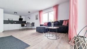 A modern living room with a sofa, coffee table, dining area, and kitchen. - Apartment "Rehkitz" in Black Forest with Balcony & Wi-Fi (Baiersbronn)