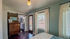 Ein Schlafzimmer mit Bett, Kommode und einem Fenster mit Vorhängen.