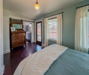 A bedroom with a bed, dresser, and a window with curtains.