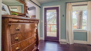Ein Zimmer mit einem Holzkasten, einer Tür mit Fenster und Blick auf Bäume.