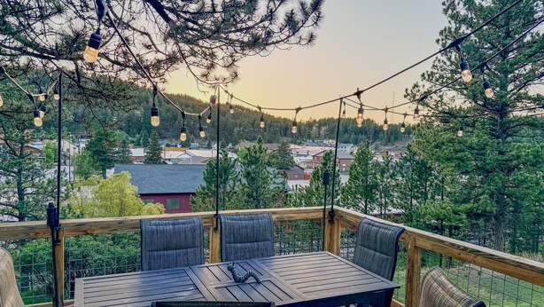 Eine Terrasse mit Tisch und Stühlen, umgeben von einem Holgitter, mit Blick auf eine Wohngegend.