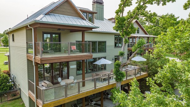 A two-story house with a balcony, outdoor seating, and a large window overlooking a yard. - Save 15% Off 4 Night Stay! Amazing Waterfall/Lake Views! Pool, Dock! (Vinita)