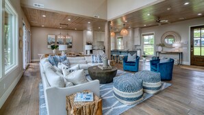 A spacious living room with a large sectional sofa, a coffee table, and blue patterned ottomans. - Save 15% Off 4 Night Stay! Amazing Waterfall/Lake Views! Pool, Dock! (Vinita)