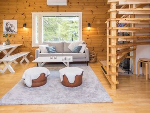 Et hyggeligt interiør med sofa, skærmstole, spisebord og en trætrap.