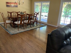 A dining area with a wooden table and chairs, a rug, and a black leather couch. - Gorgeous 2350 sq ft Ranch Home on a 14000 sq ft park-like Lot! Prime Location!! (Los Altos)