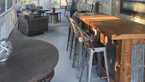 Ein überdachter Außenbereich mit Bar, Sitzgelegenheiten und Deckenventilator.
