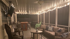 Ein Außenbereich mit Terrasse, Sitzgelegenheiten, einem Tisch und Lichterketten.