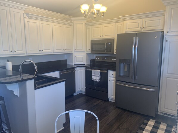 A modern kitchen with white cabinetry, a stainless steel refrigerator, a microwave, and a dishwasher.
