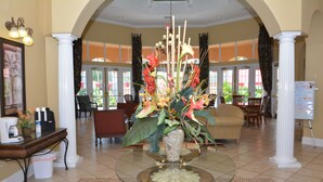 A lobby with a glass-top table, a floral centerpiece, and a reception desk. - Pool Home with Spa & Games Room in Gated Community Near WDW (Davenport)