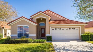 A single-story house with a red-tiled roof, a front garage, and a well-maintained lawn. - Pool Home with Spa & Games Room in Gated Community Near WDW (Davenport)