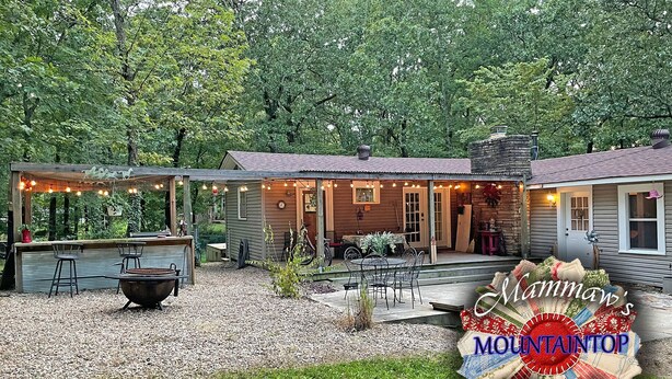 A rustic cabin with a covered patio, outdoor seating, and a fire pit.