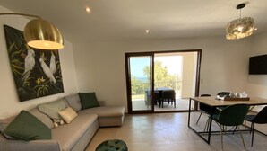 A modern living room with a sofa, ottoman, and a dining area with chairs and a table. - Residence La Listrella apt 2 (Monticello)