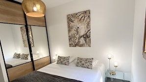 A modern bedroom with a large bed, a bedside table with a lamp, a wall-mounted mirror, and a ceiling light fixture. - Residence La Listrella apt 2 (Monticello)