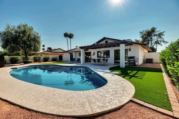 A modern house with a swimming pool, patio, and well-maintained lawn. - Perfect Getaway! Private Heated POOL, Dog Friendly, Close to ASU, Shopping & Dining! (Scottsdale)