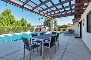 A covered outdoor area with a pool, a table with chairs, and a patio with lounge chairs. - Perfect Getaway! Private Heated POOL, Dog Friendly, Close to ASU, Shopping & Dining! (Scottsdale)