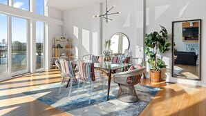 A modern dining area with a glass table, striped chairs, a large mirror, and a potted plant. - Nashville Skyline Views - 3BR/3BA, 5 Mins to Downtown (Nashville)