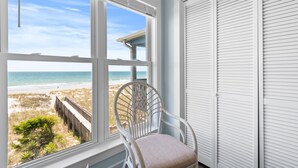 A room with a view of the beach, a white chair, and a white closet.