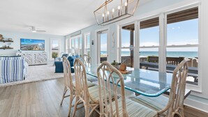 A spacious living area with a glass-top table, wicker chairs, and a view of the ocean.