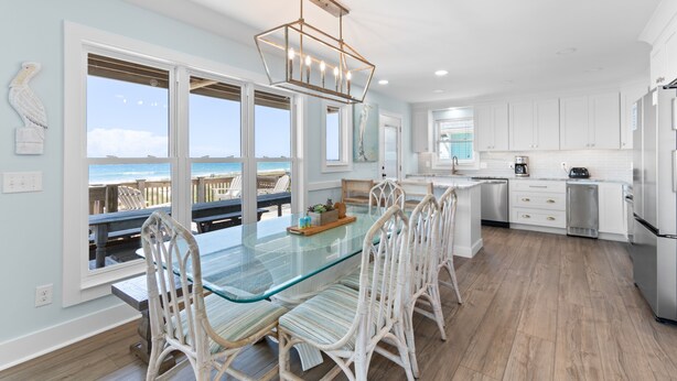 A spacious kitchen with a large island, white cabinetry, and a view of the ocean.