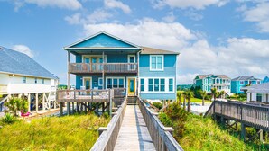 A two-story house with a wooden deck leading to the front door.