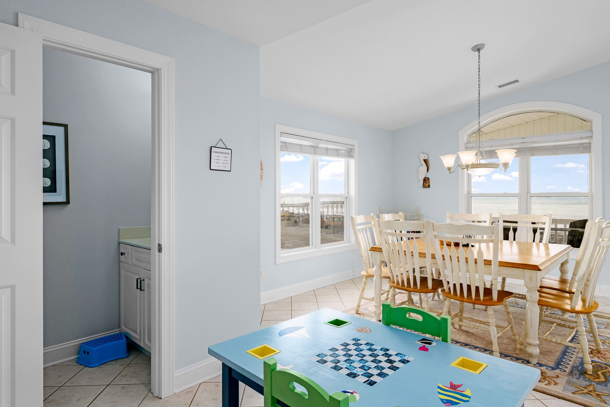 Un comedor con una mesa preparada para cuatro, una ventana con vistas y una puerta que da a la cocina.