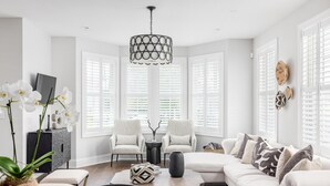 A modern living room with a sectional sofa, two armchairs, a coffee table, and a chandelier. - Designer's Dream in Historic Charleston +Walk to King St and Dining (Charleston)