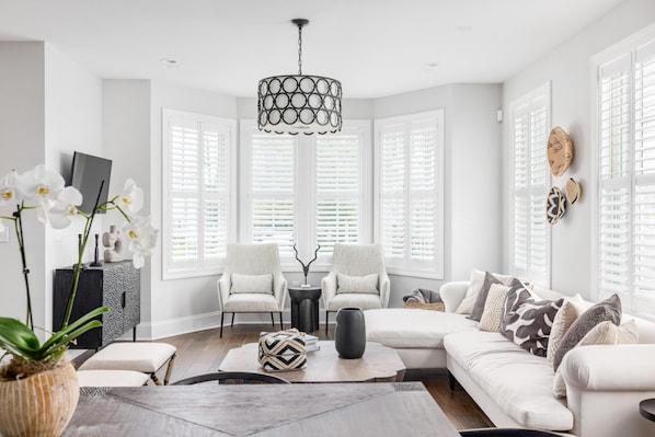 A modern living room with a sectional sofa, two armchairs, a coffee table, and a chandelier.