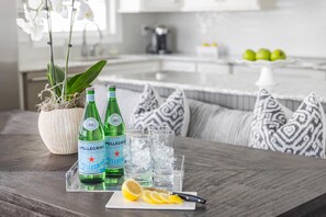 A dining table with Pellegrino water bottles, glasses, ice, and a lemon wedge.