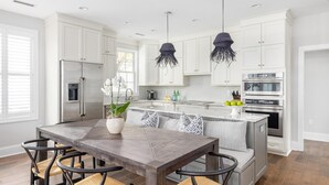 A modern kitchen with white cabinetry, stainless steel appliances, and a central island with seating. - Designer's Dream in Historic Charleston +Walk to King St and Dining (Charleston)