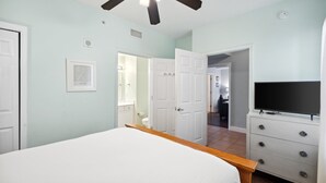 A bedroom with a bed, a TV, a dresser, and a ceiling fan. - Tidewater 1413 - 2198668 (Panama City Beach)