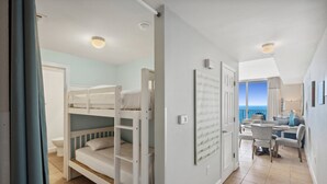 A room with bunk beds, a dining area, and a view of the sea. - Tidewater 1413 - 2198668 (Panama City Beach)