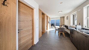 A modern hotel room with a wooden door, a dining area, and a view of the sea. - Apartment "Thalerhof Sancta Sebastianus" with Mountain View, Garden & Wi-Fi (Unterinn Ritten)