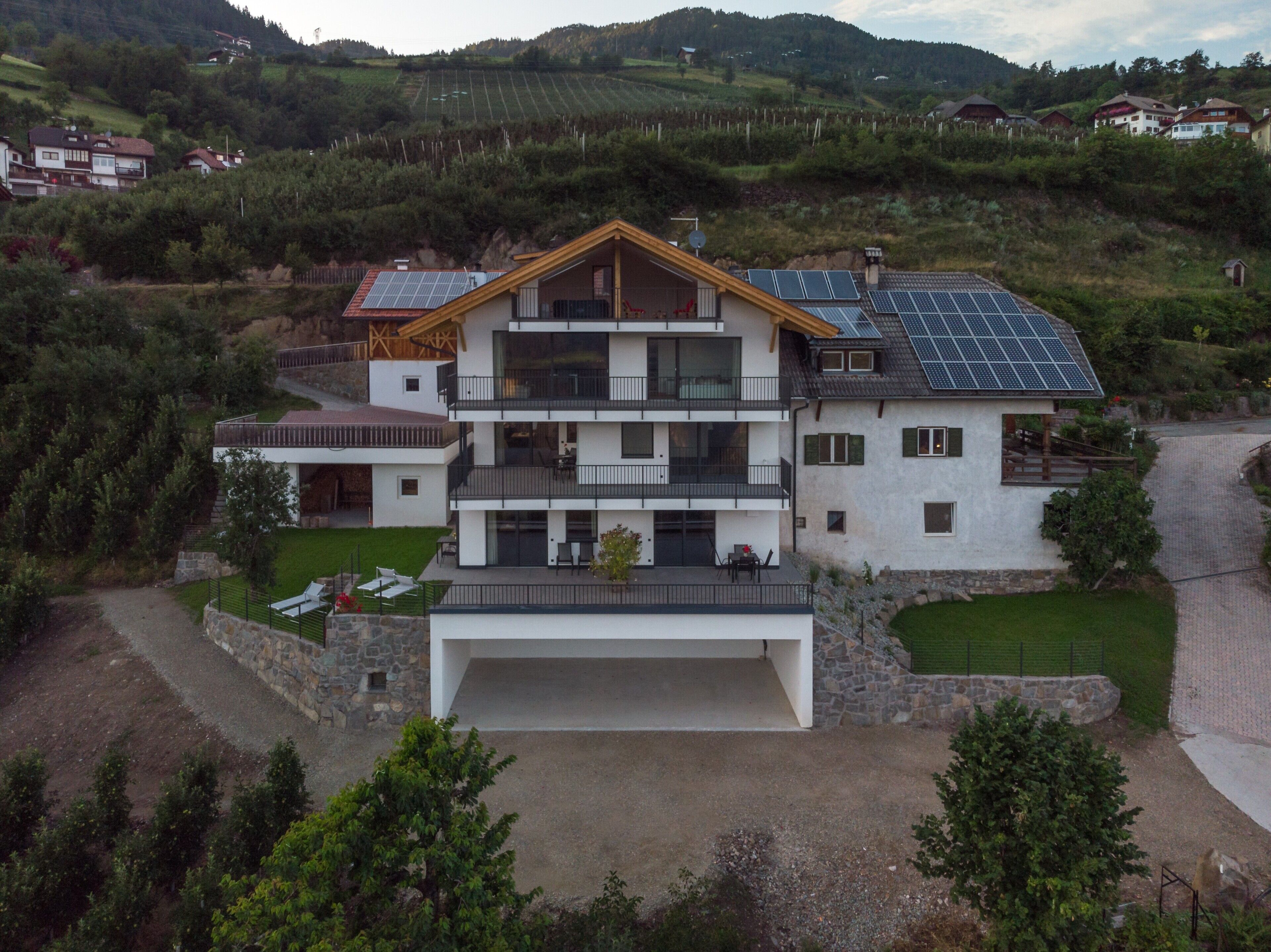 Een meerlaags huis met een garage, zonnepanelen en een balkon.