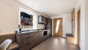 A modern kitchen with a built-in oven, a window, and a wooden door. - Apartment "Thalerhof Sancta Sebastianus" with Mountain View, Garden & Wi-Fi (Unterinn Ritten)