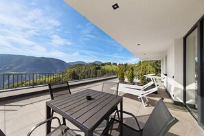 Un balcon avec une table et des chaises, donnant sur un paysage montagneux.