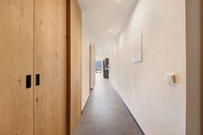 A hallway with wooden doors, a tiled floor, and a light switch on the wall. - Apartment "Thalerhof Naturae Rupes" with Mountain View, Garden & Wi-Fi (Unterinn Ritten)