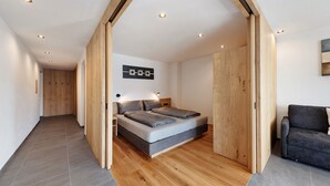 Une chambre à coucher moderne avec un lit, un plancher en bois et un canapé gris.