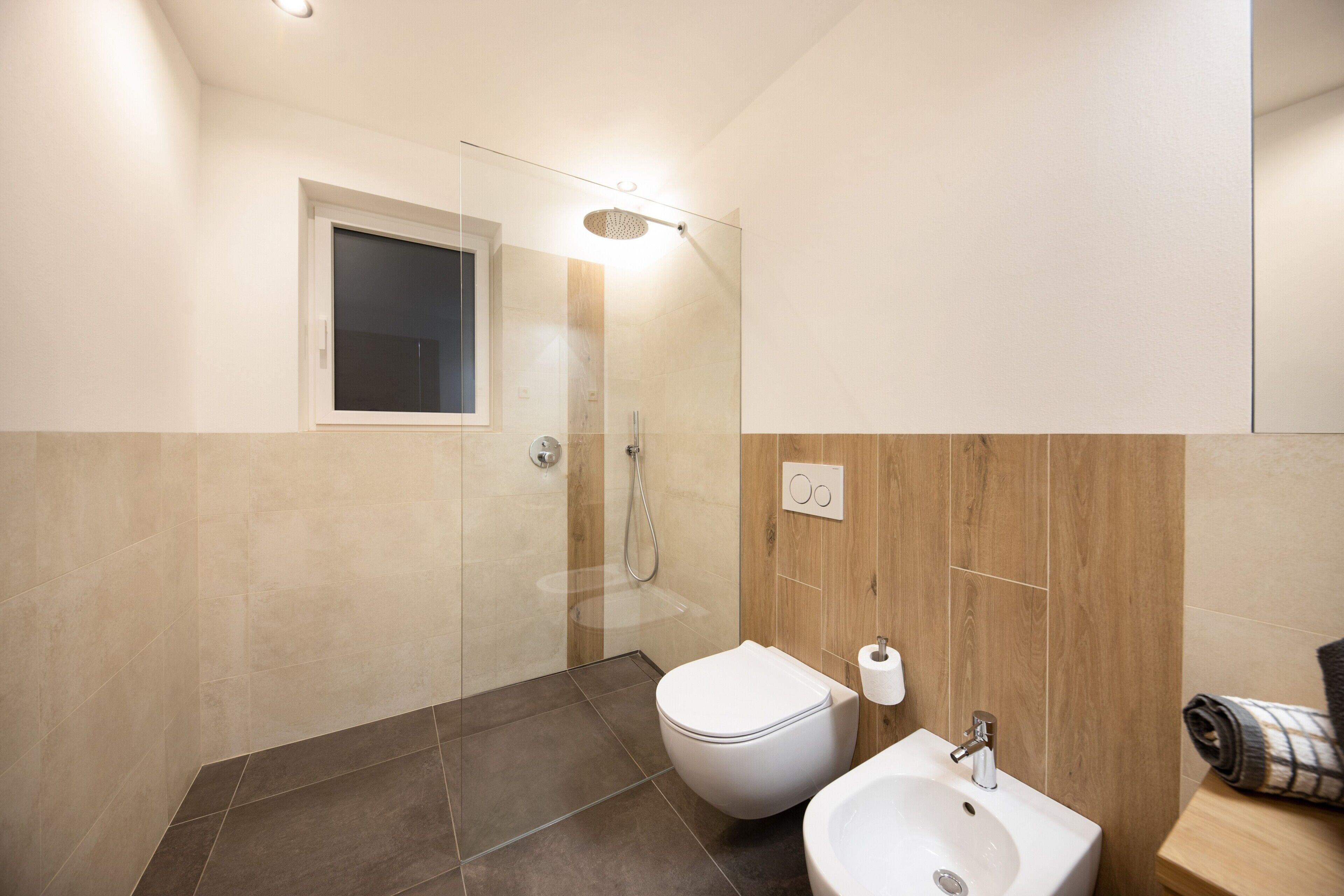 A modern bathroom with a shower, toilet, and sink.