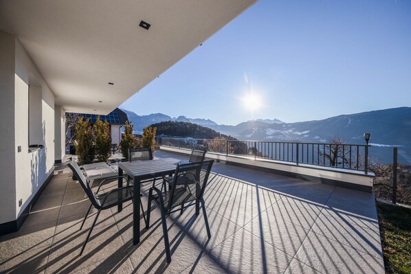 Un balcon avec une table et des chaises, donnant sur un paysage montagneux.