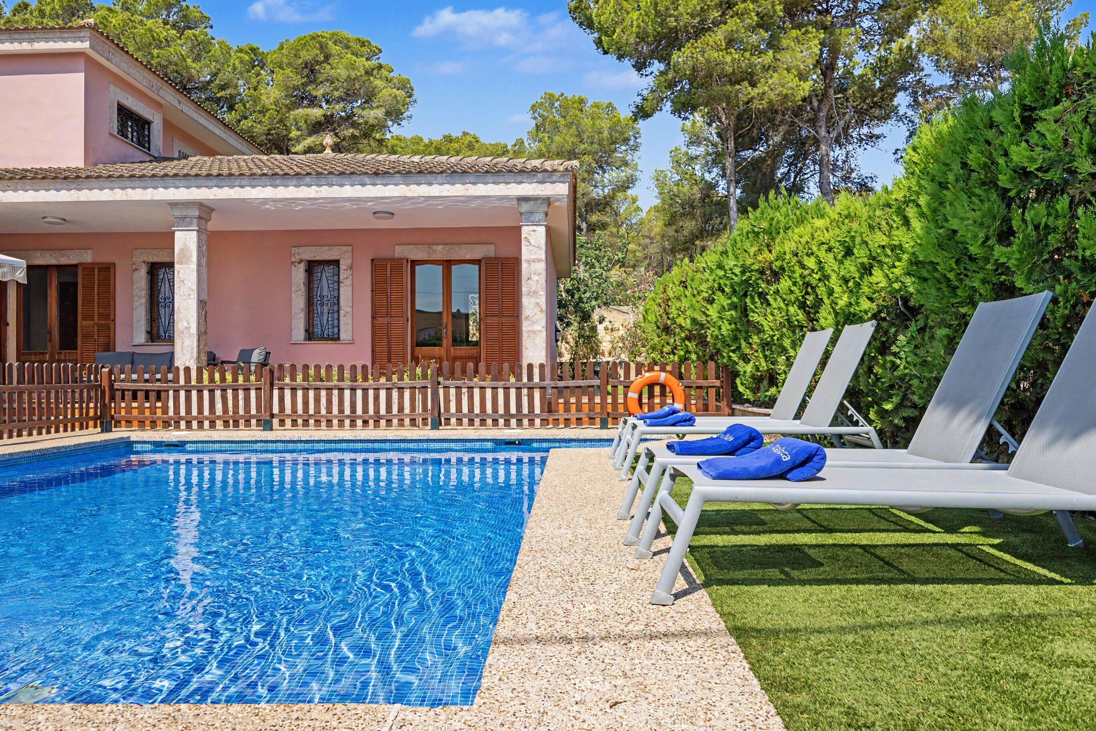 A swimming pool with lounge chairs and a wooden fence.