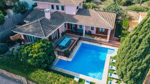 Ein zweistöckiges Haus mit Swimmingpool, einer Terrasse mit Gartenmöbeln und einem eingezäunten Garten.