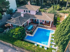 Ein zweistöckiges Haus mit Swimmingpool, einer Terrasse mit Gartenmöbeln und einem eingezäunten Garten.